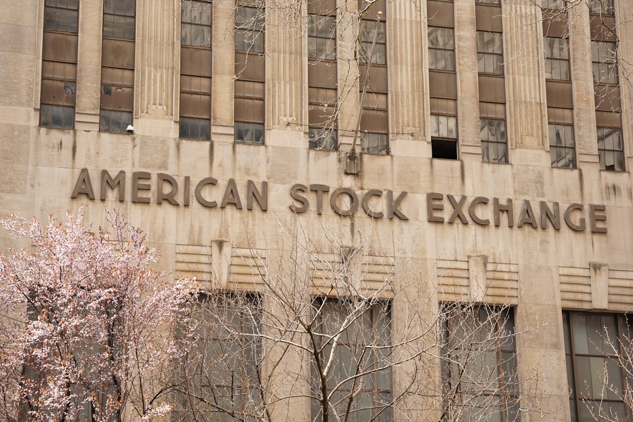 Facade of the American Stock Exchange Building in New York City during spring with blooming trees.