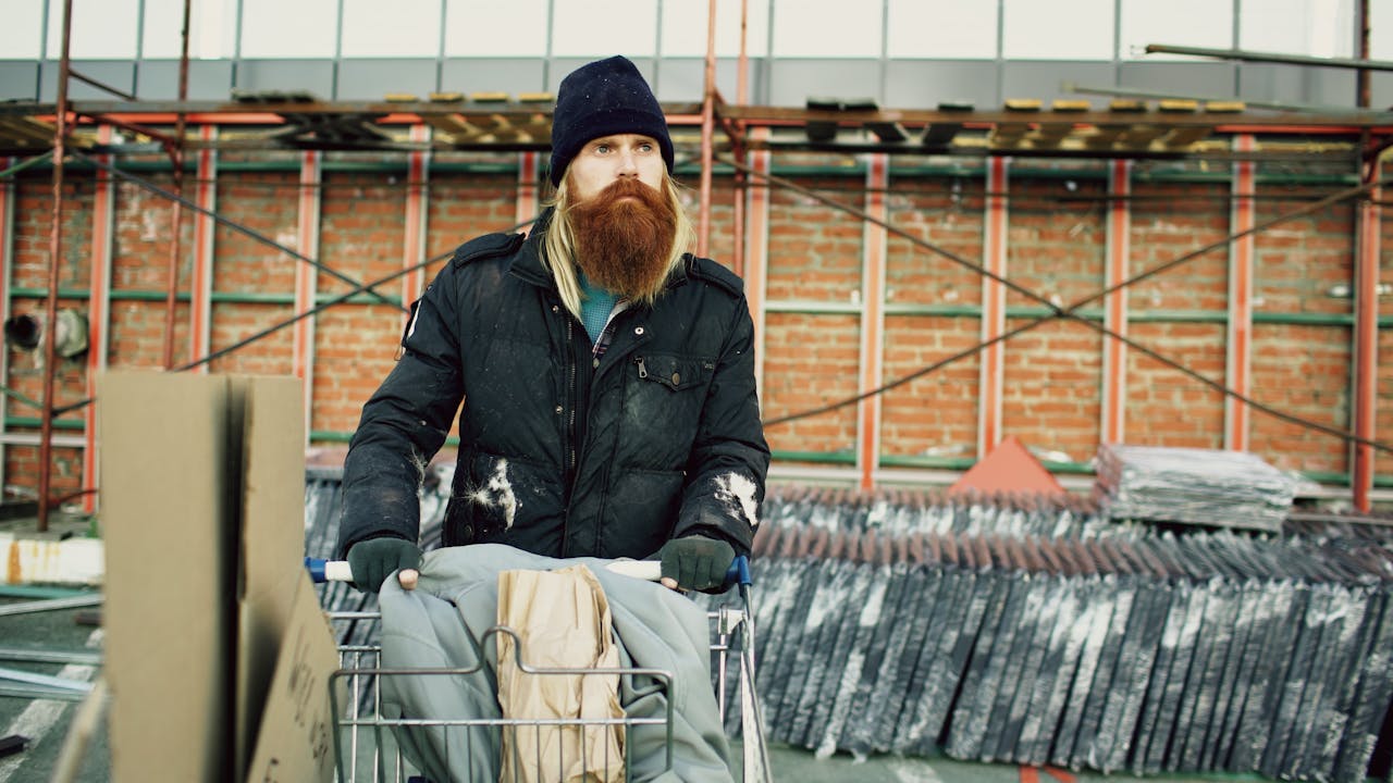 Man pushing shopping cart in a construction site, representing urban homelessness.